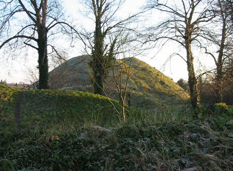 A profile view of the immense, grass-covered Norman castle motte earthwork at Castle Hill in Thetford