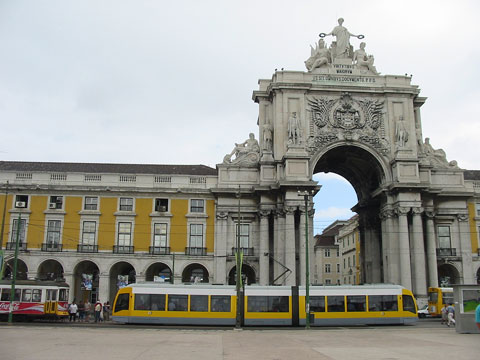 The monumental triumphal archway at Praça do Comércio with a modern tram passing by in Lisbon, Portugal