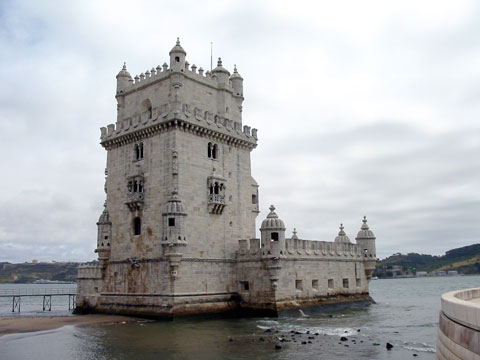 The stone architecture of the Torre de Belém sitting on the edge of the water in Lisbon, Portugal